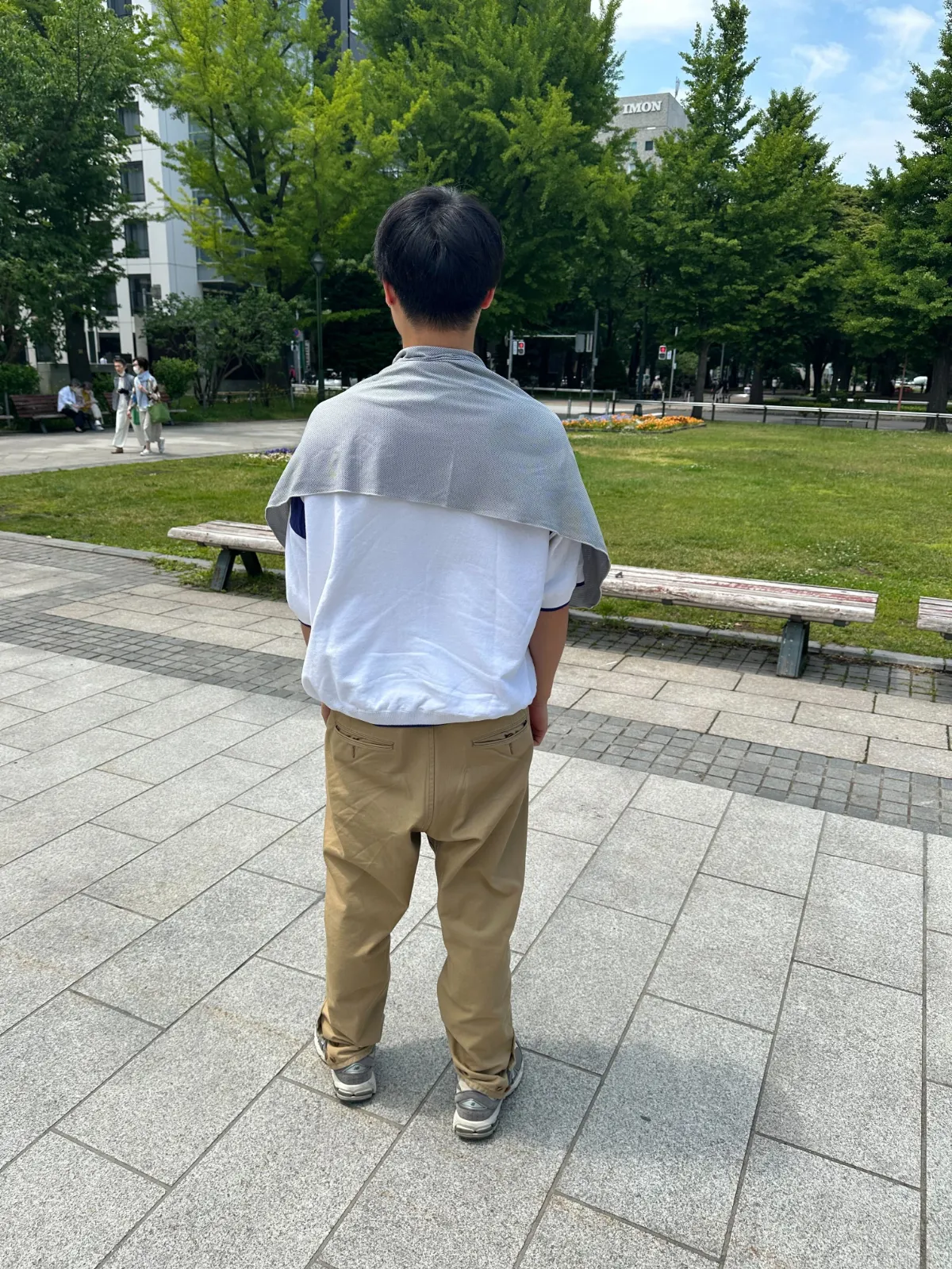 シックスパッド グレーの冷感タオルを男性が首にかけている後ろからの様子